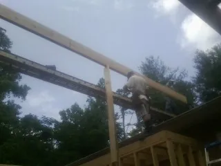 Carpenter setting a ridge beam over a new addition frame in Geneva