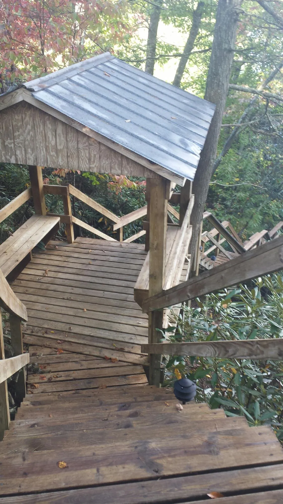 Metal roofed shelter over wooden steps on a wooded walkway — Skylight Repair & Installation work by our crew in Geneva